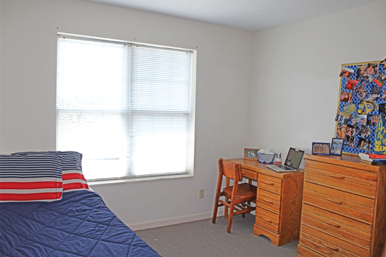 A bedroom inside of an apartment in Young Hall. The room includes a bed, desk, and dresser.